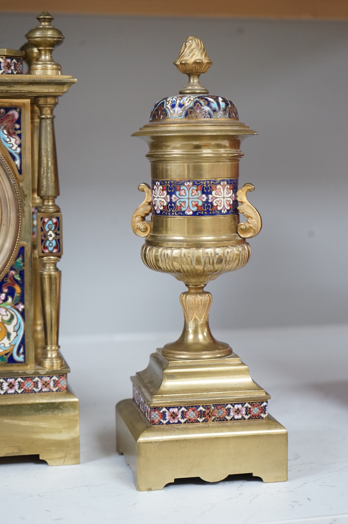 A large early 20th century French brass and champlevé enamel clock garniture, 35cm high